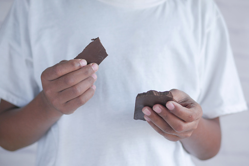 young man eating dark chocolate close up .