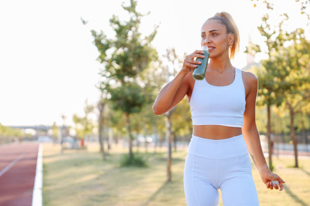 femme buvant un smoothie aux légumes après l’entraînement de course de fitness - juice drinking women drink photos et images de collection