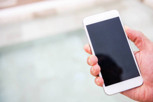 This is a photograph of a man in his 40s holding a mobile phone while on vacation in Mexico.