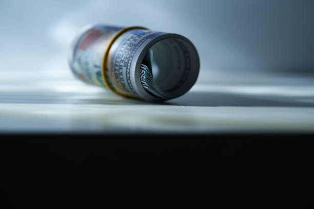 istock roll of 100 dollar bills against gray background 1414825619