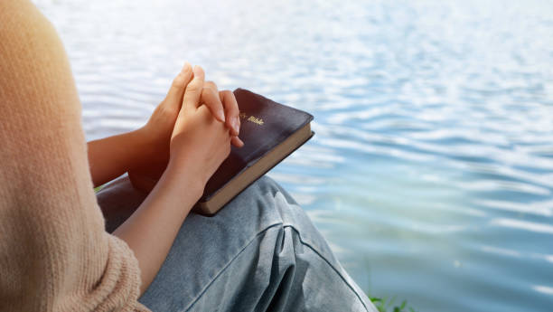 woman hands holding bible and praying at river in the morning - batismo imagens e fotografias de stock