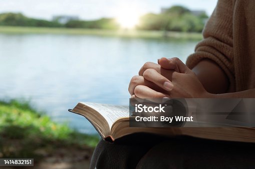 istock Woman hands praying with a bible in his legs Outdoors 1414832151