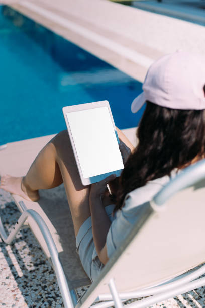 istock Woman using digital tablet near the pool, enjoying her vacation 1414838701