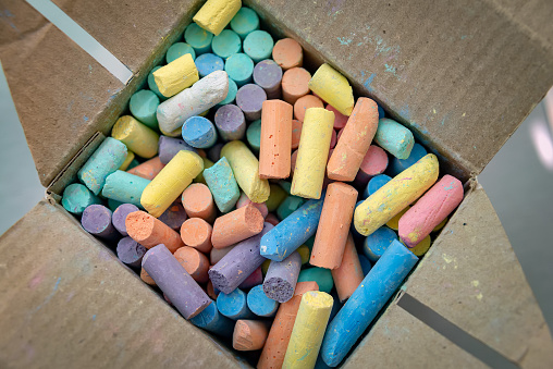Many colorful chalks in a cardboard box. Top view