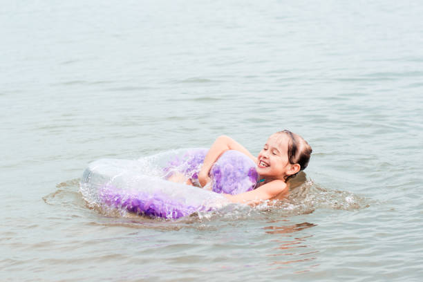 fröhliches mädchen, das sich an einem aufblasbaren ring im fluss festhält. lokaler tourismus. sommerferien - swim ring stock-fotos und bilder