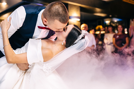 Bride and groom kiss each other tender after their first dance.