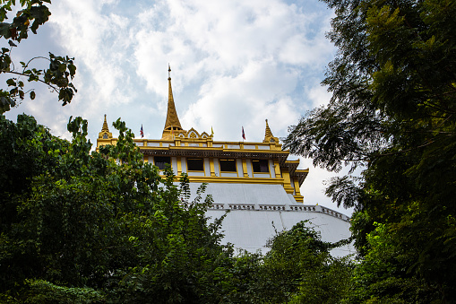 The Golden Mount Temple Over Blue Sky Against Green Trees  In Bangkok Thailand Southeast Asia \nLow Angle View