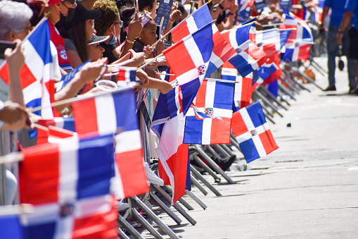New Yorkers of all ages are holding Dominican flags during the Dominican Day Parade on Sixth Avenue in New York City.