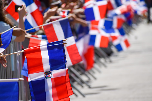 New Yorkers of all ages are holding Dominican flags during the Dominican Day Parade on Sixth Avenue in New York City.