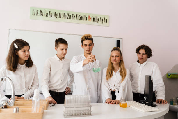 nauczyciel chemii szkolnej pokazuje dzieciom kolby z płynami do eksperymentów w laboratorium. koncepcja edukacji. lekcja grupowa kolegów z klasy na lekcji chemii. - scholastic aptitude test zdjęcia i obrazy z banku zdjęć