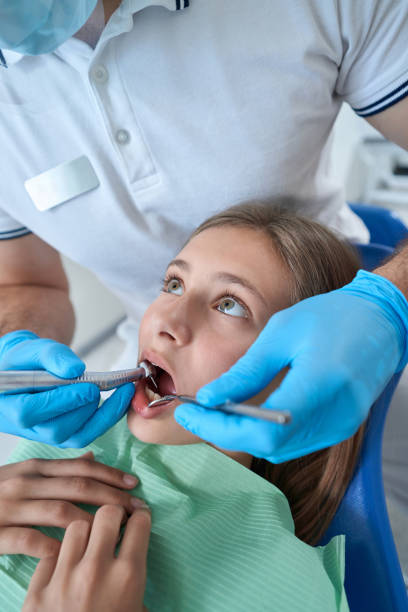 istock Pediatric dentist using medical equipment for treating caries in patient 1414856588