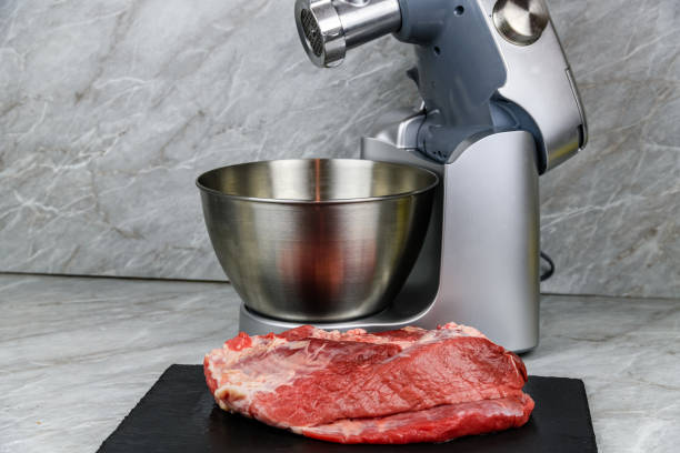 modern food processor with meat grinder and peace of pork meat on a kitchen table - meat grinder ground beef meat imagens e fotografias de stock