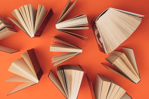 Creative pattern made of books on bright orange background. Education and  knowledge concept. Flat lay.