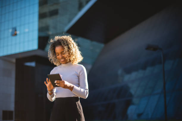 istock woman using tablet in front of a mirrored building 1414863131