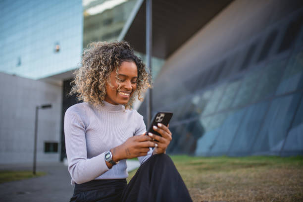 istock woman using smartphone in front of a mirrored building 1414863155