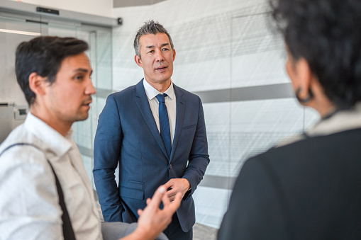 A multiracial group of mixed age businessmen and businesswomen wearing suits,  enjoying their discussion.