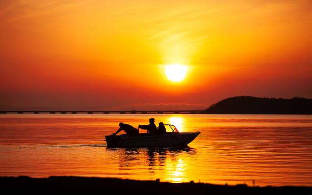 sagoma di una barca con pescatori - silhouette three people beach horizon foto e immagini stock