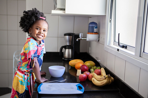 Portrait of little girl eating fruits in the kitchen