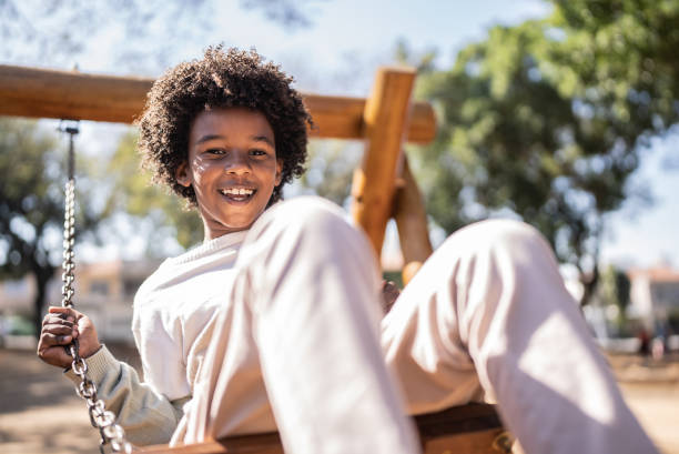 portret szczęśliwego chłopca bawiącego się na huśtawce - child swinging playground african descent zdjęcia i obrazy z banku zdjęć