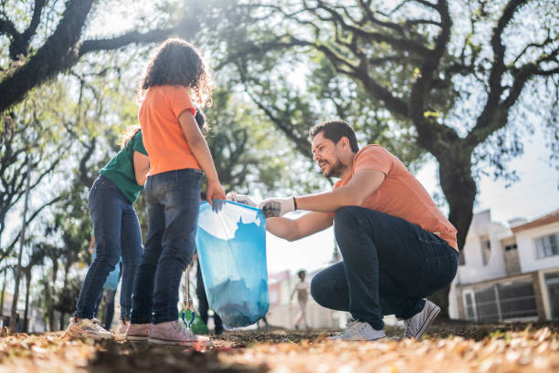 istock Father and daughters picking up garbage at a public park 1414876194