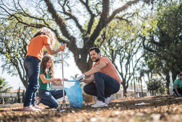 istock Father and daughters picking up garbage at a public park 1414876212