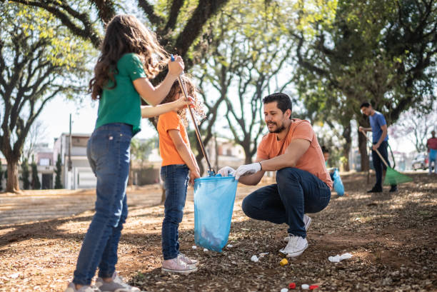 istock Father and daughters picking up garbage at a public park 1414876219