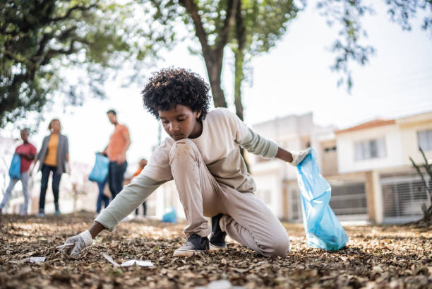 istock Boy picking up garbage to clean a public park 1414876239