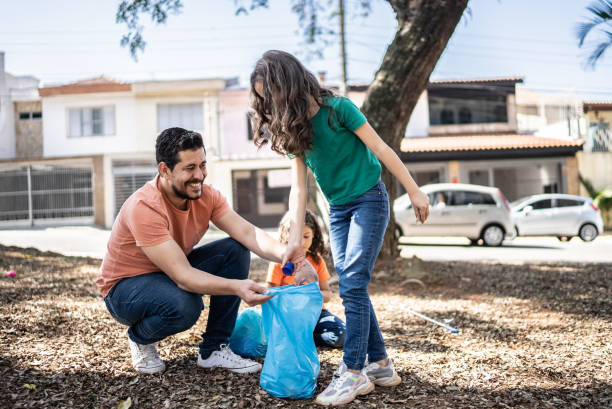 Father and daughters picking up garbage at a public park