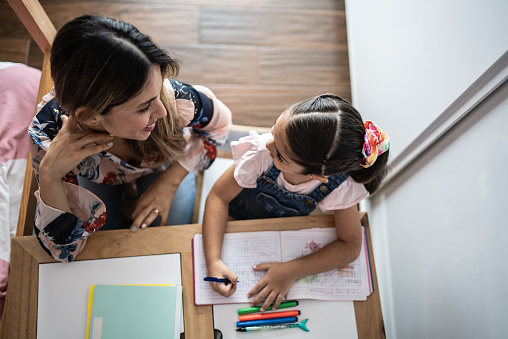 Mother and daughter doing homework in the bedroom at home