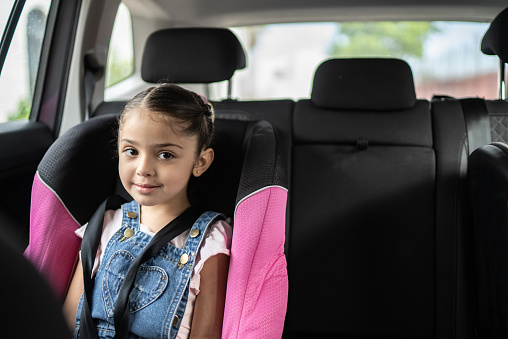 Little girl being driven to school in the backseat of a car