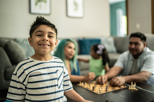 Portrait of a little boy playing chess with his family at home