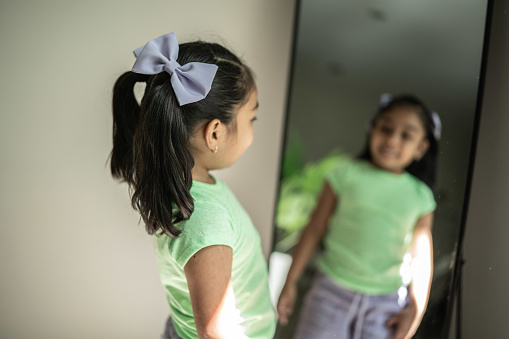 Child girl looking in the mirror at home