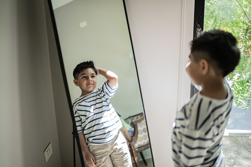 Child boy looking in the mirror at home