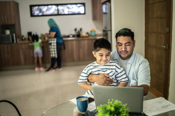 istock Father working with his son using laptop at home 1414877769