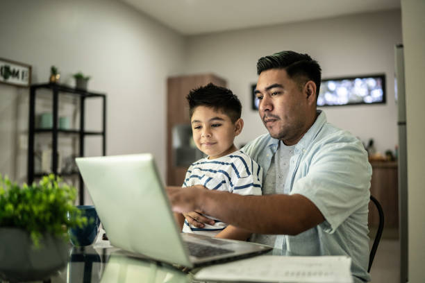 istock Father working with his son using laptop at home 1414877777