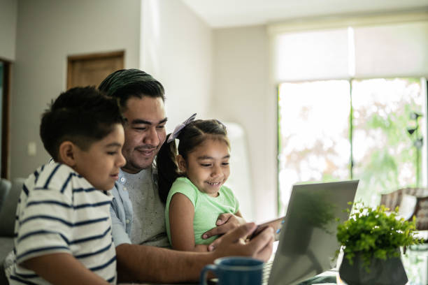 istock Father with his kids using laptop and mobile phone watching something at home 1414877827