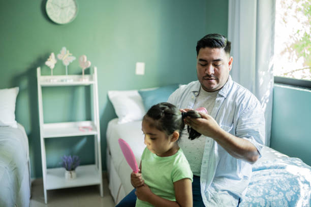istock Father combing daughter's hair at home 1414877873