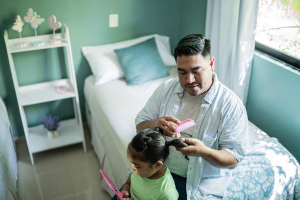 istock Father combing daughter's hair at home 1414877879