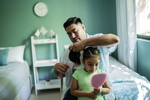 Padre peinando el cabello de la hija en casa photo