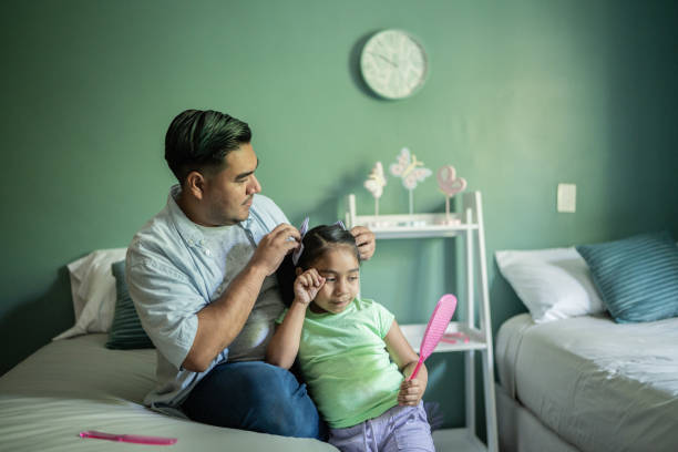 istock Father combing daughter's hair at home 1414877889