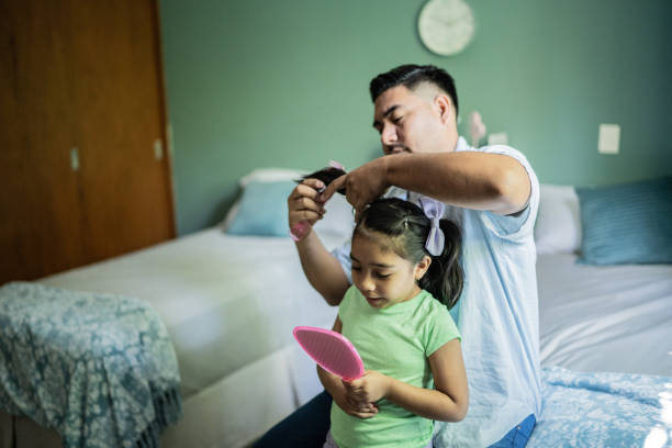 istock Father combing daughter's hair at home 1414877894
