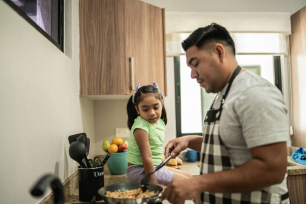 padre cocinando mientras habla con su hija en la cocina de casa - mexican pots fotografías e imágenes de stock