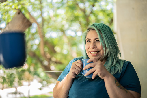 Mid adult woman drinking a cup of coffee and talking to her husband at home