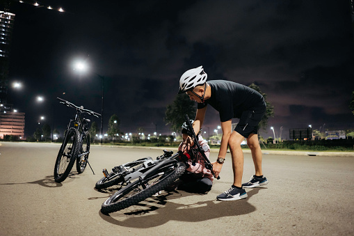 man helping his girlfriend to get up after falling from a bicycle.