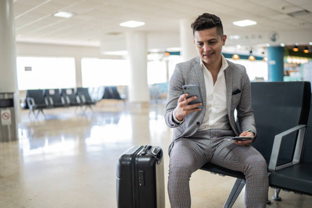 istock Businessman using mobile phone while waiting for boarding at airport 1414879633