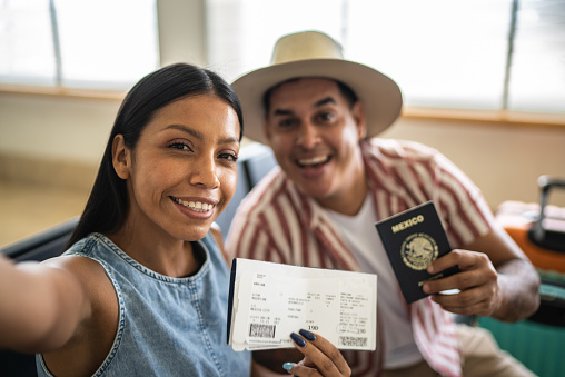 istock Couple taking a selfie with passport and airplane ticket - Camera point of view 1414879935