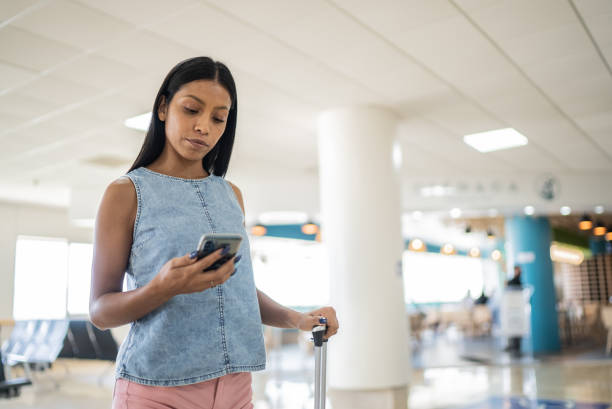 istock Young woman using phone at airport 1414880911