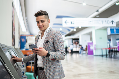 Businessman doing check-in and using phone at the airport