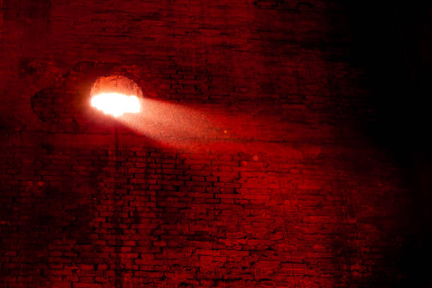 Hole in a brick wall with light passing through stock photo
