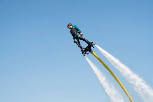 Hydrofyler jet boots operation. Young man riding flyboard jetski on water. Summer fun activity. Hydro flying jetpack board attached to water craft June 10, 2022. Barnaul Russia: Hydrofyler jet boots operation. Young man riding flyboard jetski on water. Hydro flying jetpack board attached to water craft. Summer fun activity. turbojet engine photos stock pictures, royalty-free photos & images